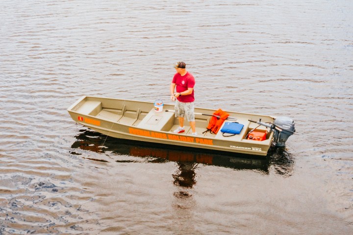 Person in red shirt on a motorboat in calm water.