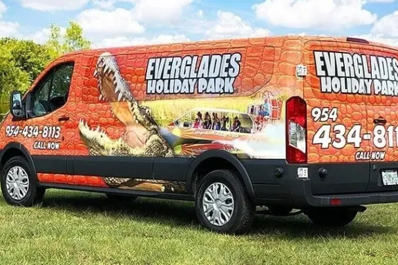 Orange van with Everglades Holiday Park graphics and contact info on side.