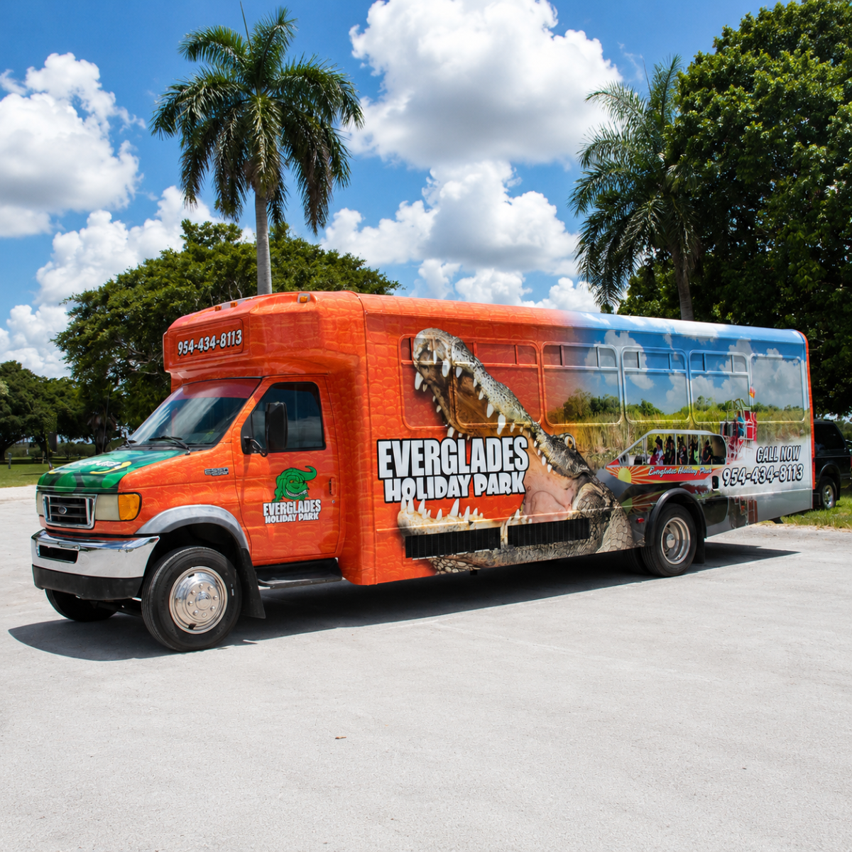 Colorful Everglades Holiday Park bus with alligator graphic parked near palm trees.